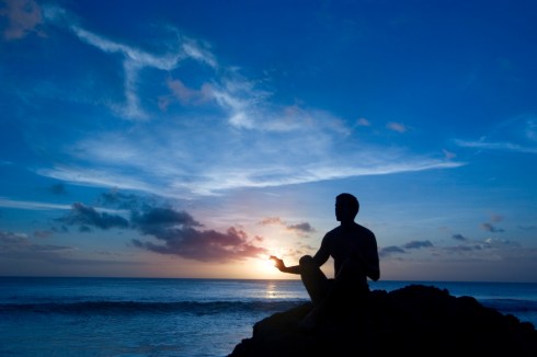 man meditating by ocean sunset